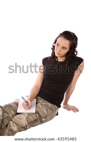 A woman in army clothes writing a letter home with a sad expression on her face.