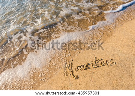 Mauritius inscription in the sand about to be erased by a wave. Closeup picture of inscription on the sand.