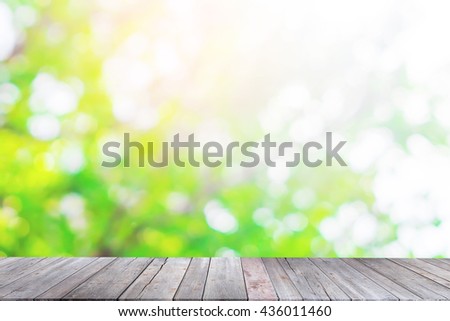 Wood table top on blurred green background of tree green color background.- can be used for montage or display your products