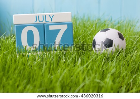 July 7th. Image of july 7 wooden color calendar on greengrass lawn background. Summer day, empty space for text