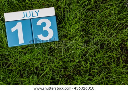July 13th. Image of july 13 wooden color calendar on greengrass lawn background. Summer day, empty space for text