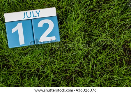 July 12th. Image of july 12 wooden color calendar on greengrass lawn background. Summer day, empty space for text