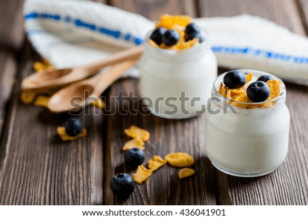 Yogurt with fresh blueberries, corn flakes on a textural brown surface
