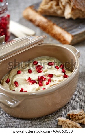 appetizing humus decorated with garnet grains in a cooking pot Royalty-Free Stock Photo #436063138