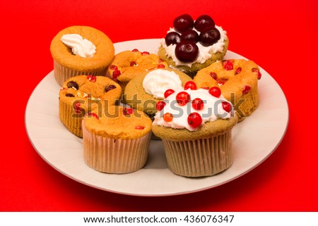 Fruit cupcakes on a plate isolated on red background