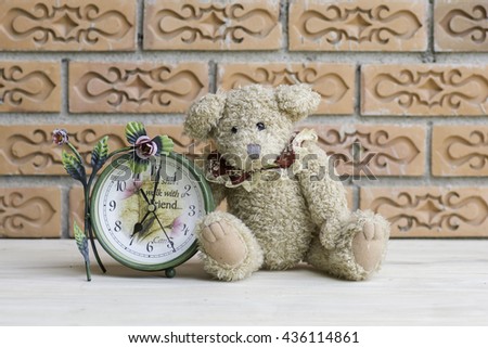 Teddy bear with clock on brick wall background.
