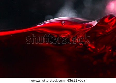 Red wine on black background, abstract splashing. Royalty-Free Stock Photo #436117009