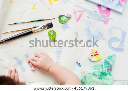 Top view of kid and his mother painting with watercolor paints on the paper.
