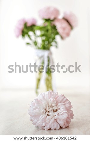 a flower and a vase with flowers in the background
