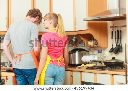 Couple woman and man in apron cooking preparing dinner food in kitchen together.