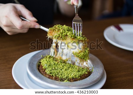 Turkish dessert kunefe with pistachio powder in silverl plate at restaurant Royalty-Free Stock Photo #436210003