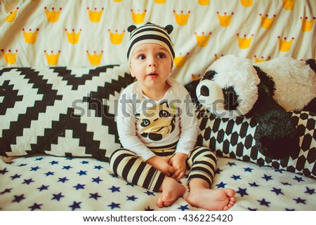 funny little boy dressed as a panda sitting on a bed
