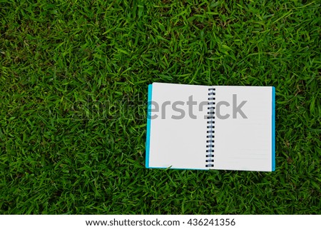 Notebook on green grass background