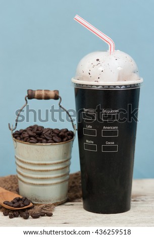 Iced coffee with coffee beans on wood vintage background,Selective focus on paper cup
