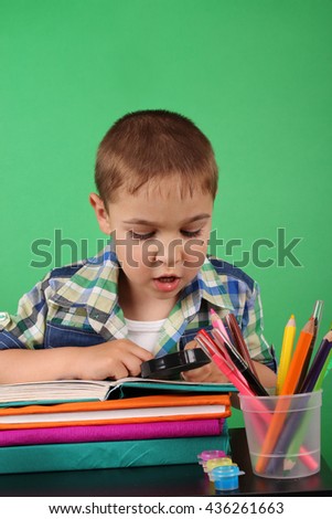 Book, school, kid. School boy at the classroom working with magnifying glass. Photo of teen, creative concept with Back to school theme. Young student reading a book. Concept of knowledge day.