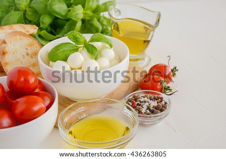 Italian food ingredients, mozzarella, tomatoes, basil and olive oil on white background, selective focus, copy space