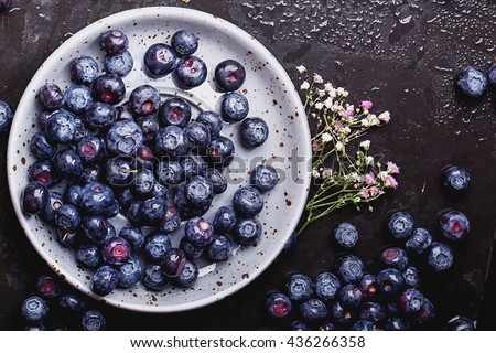 Organic blueberries served in the grey vintage cup over a black slate board and dark metal background. Dark Rustic Style. Concept Healthy Food