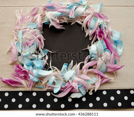 Top view of floral wreath frame with blue and pink petals isolated on wooden background with free space for text.
