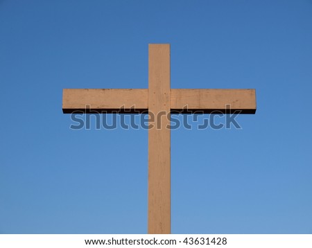 A wooden Christian cross over a blue sky