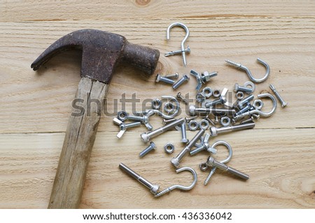 Screw hooks and hammer made of stainless steel on the wood background.