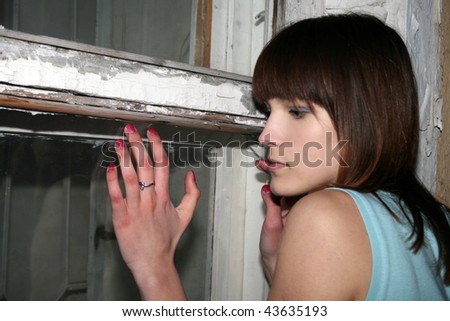 Teenage girl standing near old window