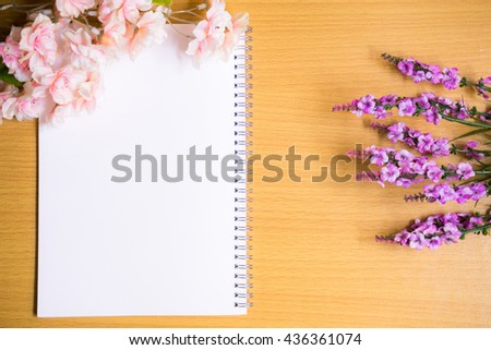 Fresh flower arrangements on book white page, lying on wooden table. Vintage style.