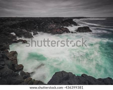 Dramatic volcanic coastline with waves breaking against cliffs in Grindavik, Iceland. Long exposure photography.