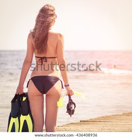 Young slim woman with snorkelling equipment standing near sea. Caucasian girl with flippers, mask and snorkel. Scuba diving or snorkel background