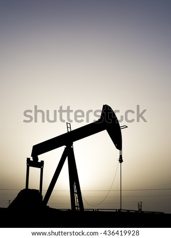 Sunset and silhouette of crude oil pump in oilfield 