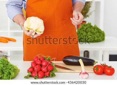 Mid section of a man preparing to chop cauliflower in the kitchen at home.