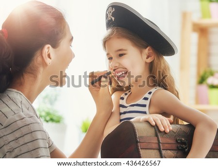 Happy family is preparing for a costume party. Mother and her child girl playing together. Girl in pirate's costume. 