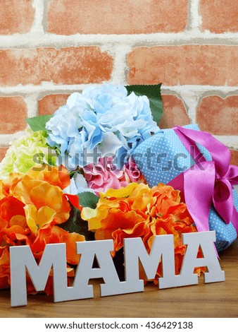 bunch of flowers with a gift box and word mama on wooden background