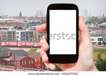 travel concept - tourist photographs Copenhagen city, Denmark from seaport on smartphone with cut out screen with blank place for advertising