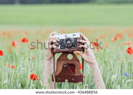 Photographing girl in a poppy field