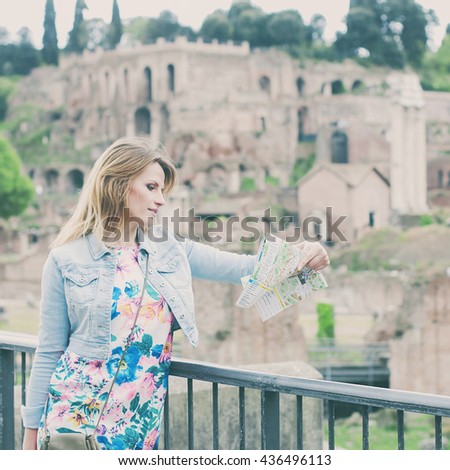Pretty female tourist looking a map  on the ruins of the Roman Forum in Rome, Italy, selective focus and square image