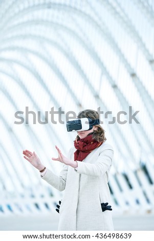 Woman wearing a virtual reality headset, controlling the experience with hand gesture - touching and controling immaginare surfaces