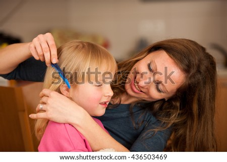 Mother combs hair to a cute little girl