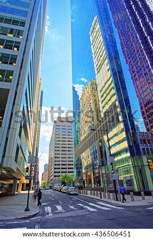 Street view with skyscrapers reflected in glass in the City Center of Philadelphia, Pennsylvania, USA. It is central business district in Philadelphia. Tourists in the street
