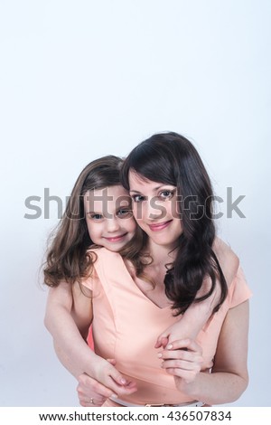 Little girl hugging her mom around the neck from behind