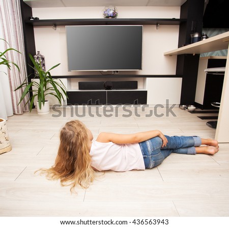 Child watching TV at home. Girl looking at television