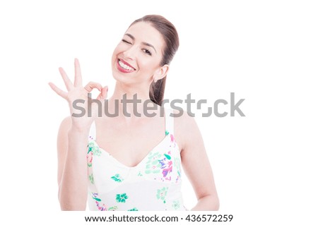 Pretty lady in a summer dress making okay gesture and winking isolated on white background with copy text space