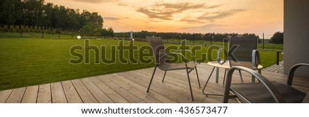 Panoramic view of new villa patio with simple furniture set, sunset view