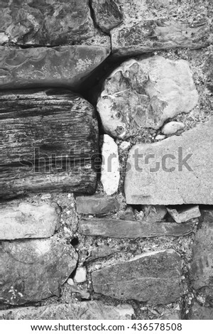 Stone and timber construction. Fragment of old farmhouse wall. Abstract vintage background. Black and white photo.