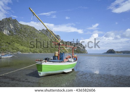 traditional fishing boat laying on a beach near the sea with mountain and island, beautiful blue sky and cloud ,colorful picture style, wide angle