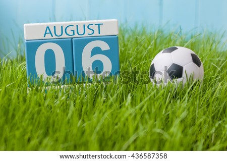 August 6th. Image of august 6 wooden color calendar on green grass lawn background with soccer ball. Summer day. Empty space for text