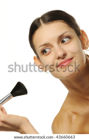 The pretty woman with a brush for a make-up. It is isolated on a white background.