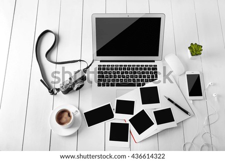 Laptop, phone, photos and cup of coffee on a wooden planks background, top view
