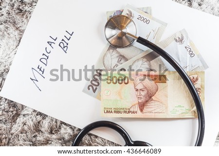 Stethoscope with wording of "Medical Bill" showing expensive healthcare or expensive medical bill with Indonesia Rupiah Bank Notes