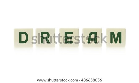 Word "Dream" on board game square plastic tile pieces, isolated on a white background.