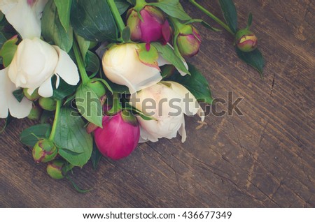Peony background. Fuchsia, pink and white peonies on wooden table with place for text. Spring flower peony. Happy Mothers Day. Mother's Day greetings card. Mothers Day gift. Copy space. Toned image.